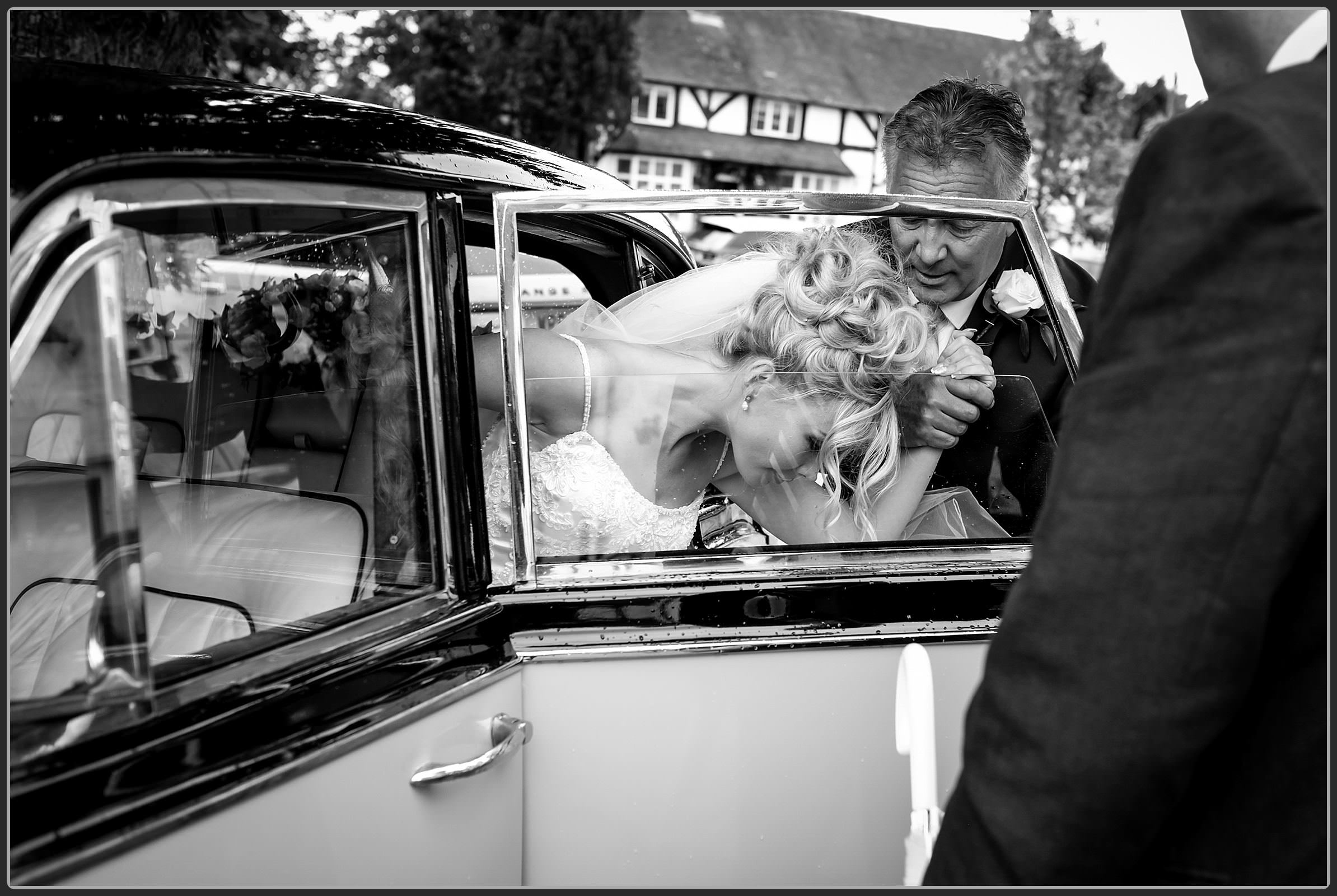 Brides dad helping her get out the wedding car