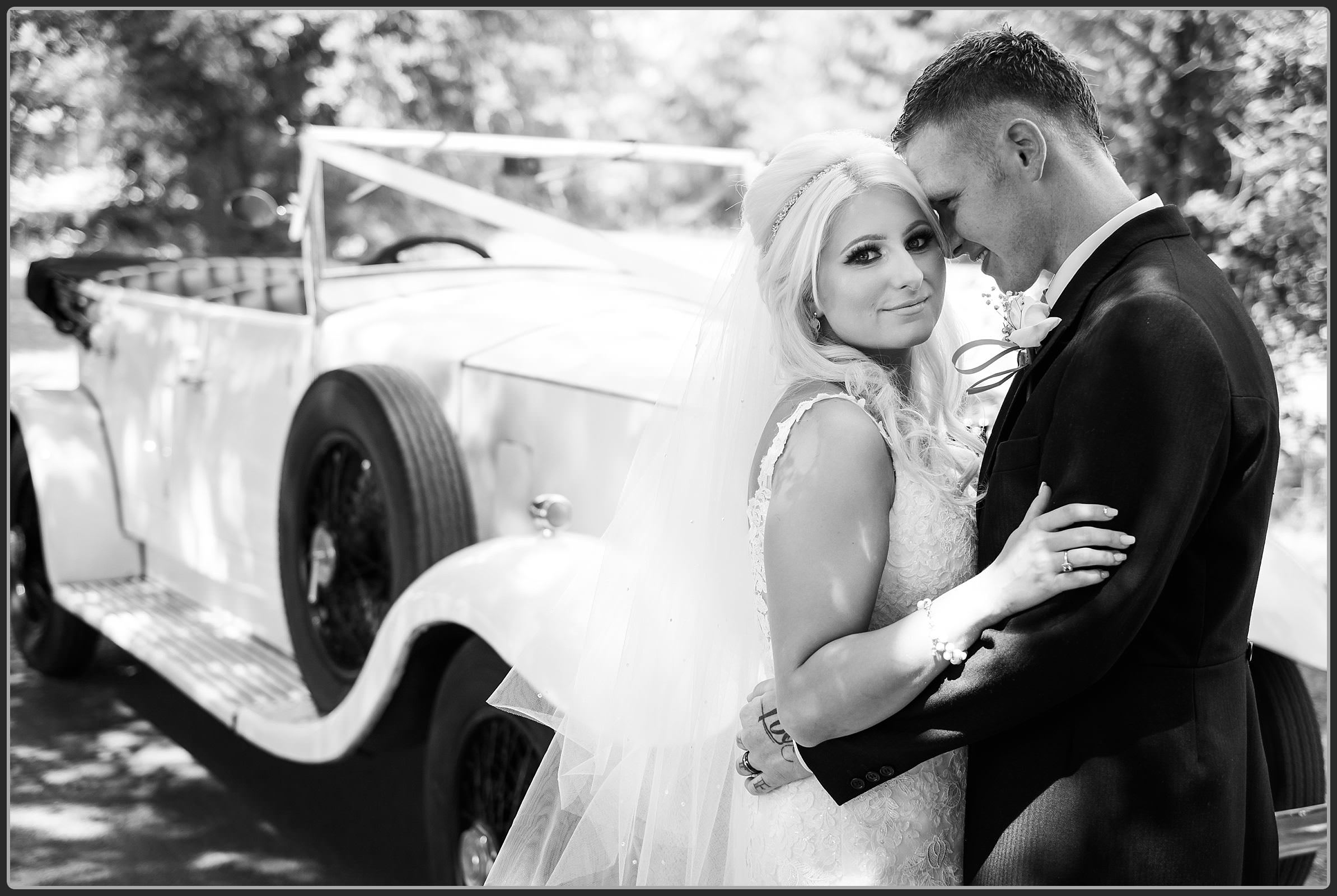 Bride and groom with the wedding car